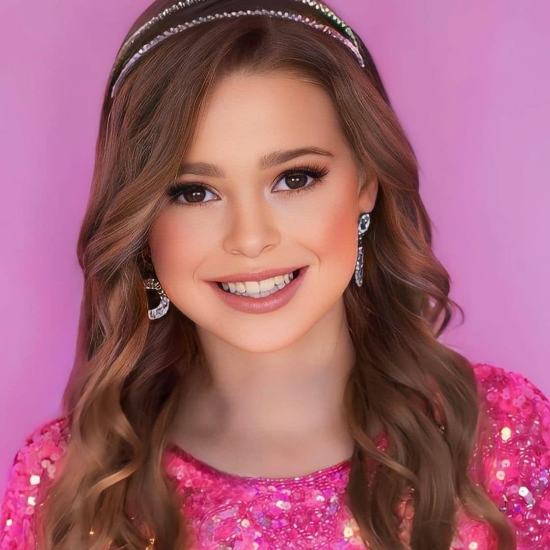 Smiling woman with pink dress and wavy hair.