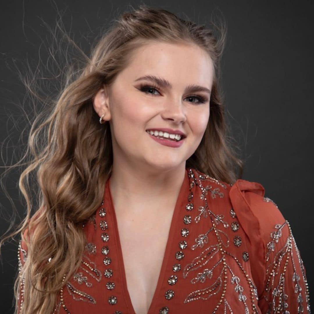 Smiling woman with wavy hair in red outfit.