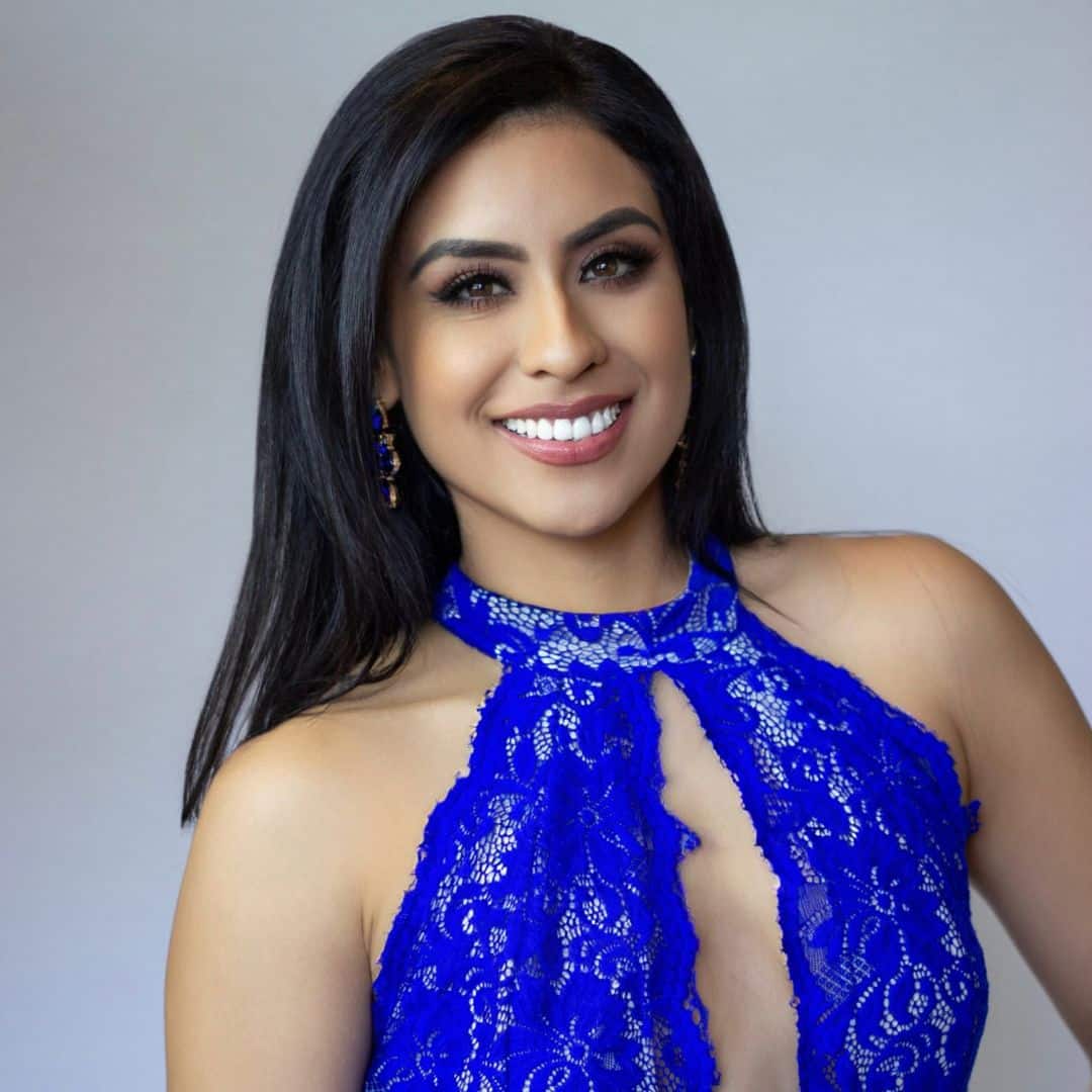 Smiling woman in blue lace dress.