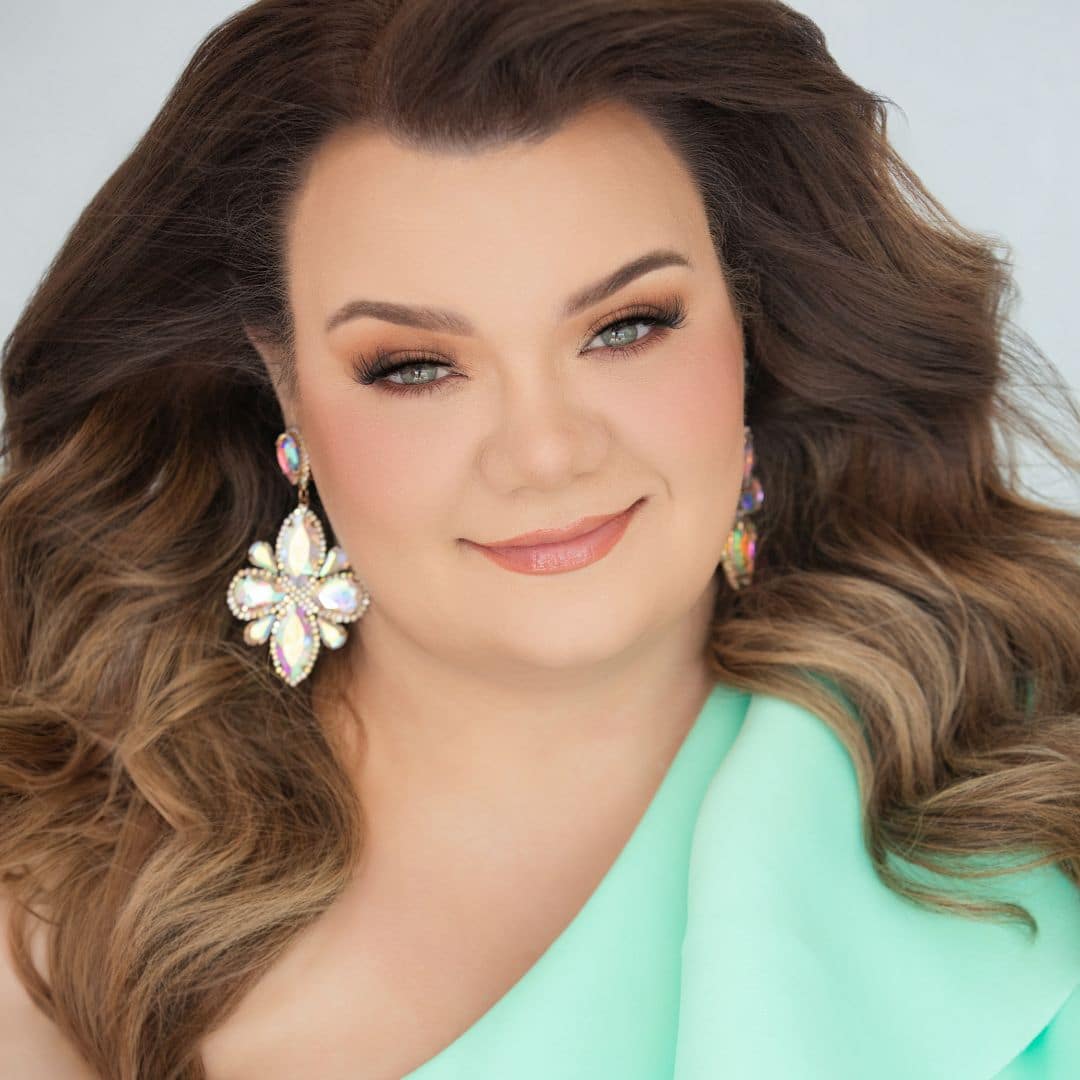 Smiling woman with wavy hair and large earrings.