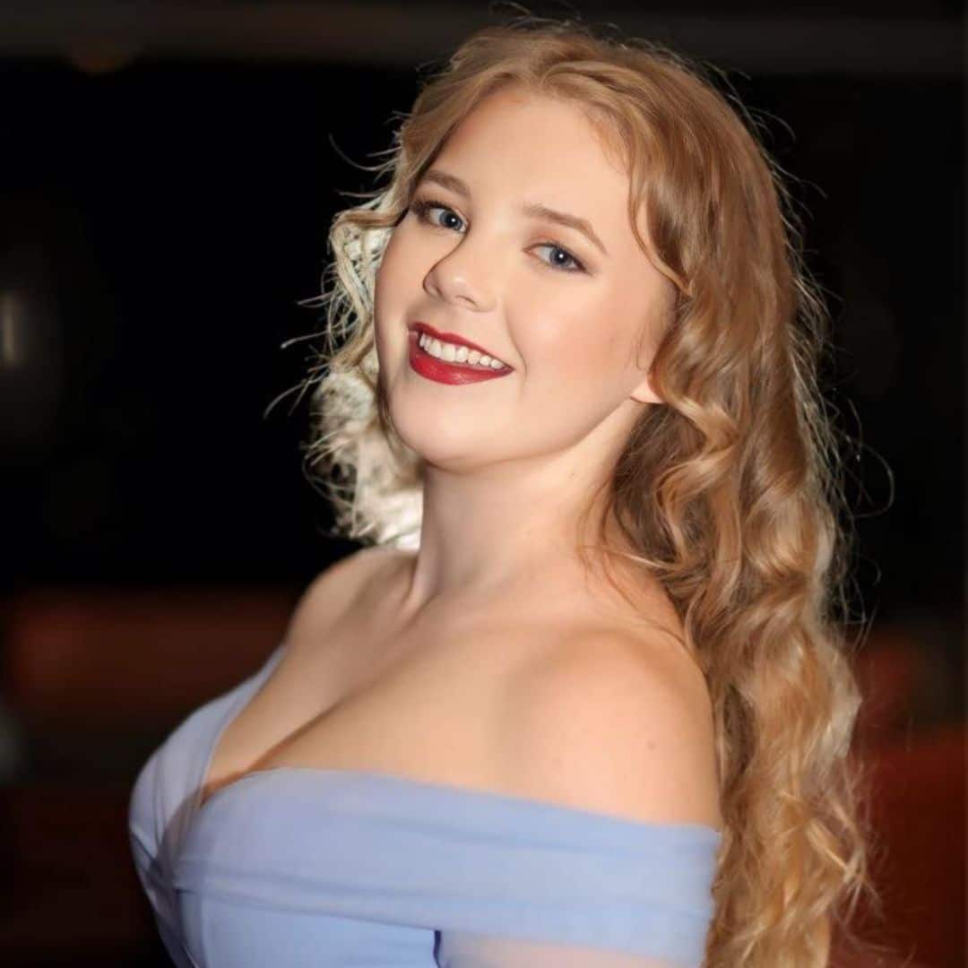 Smiling woman with curly hair in blue dress.