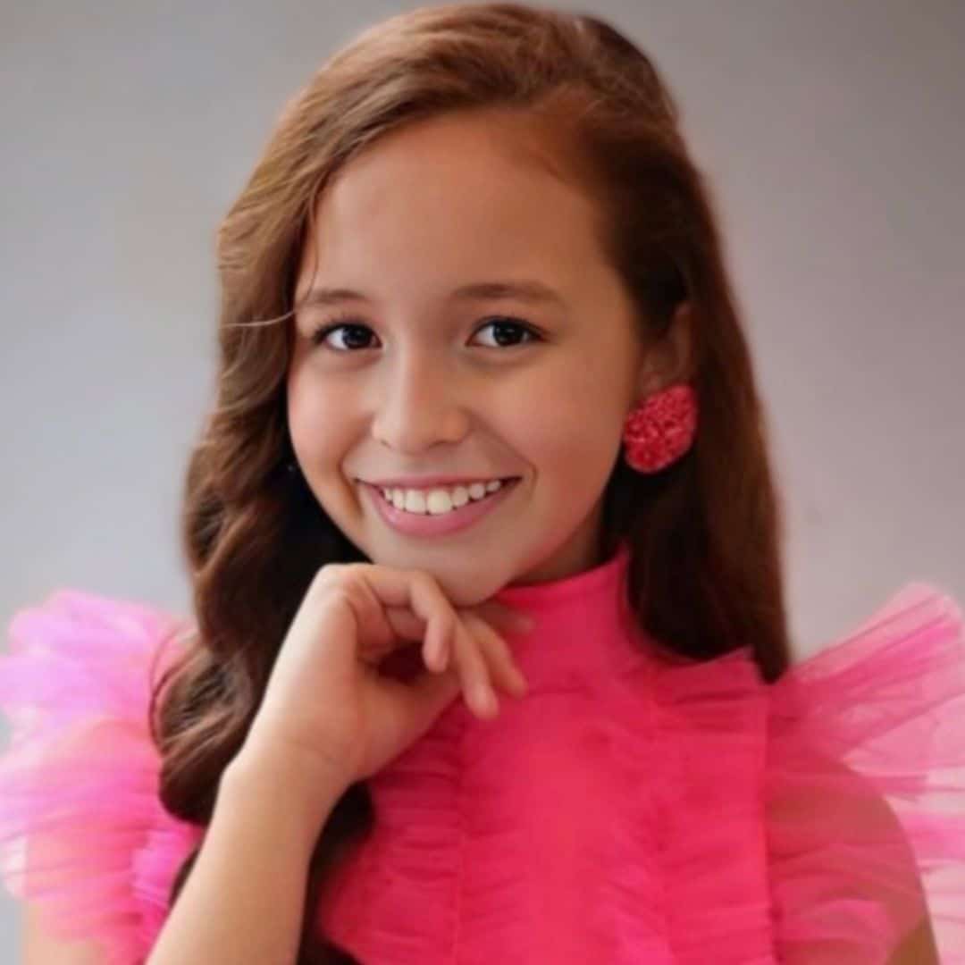 Smiling girl in pink dress and matching earrings.