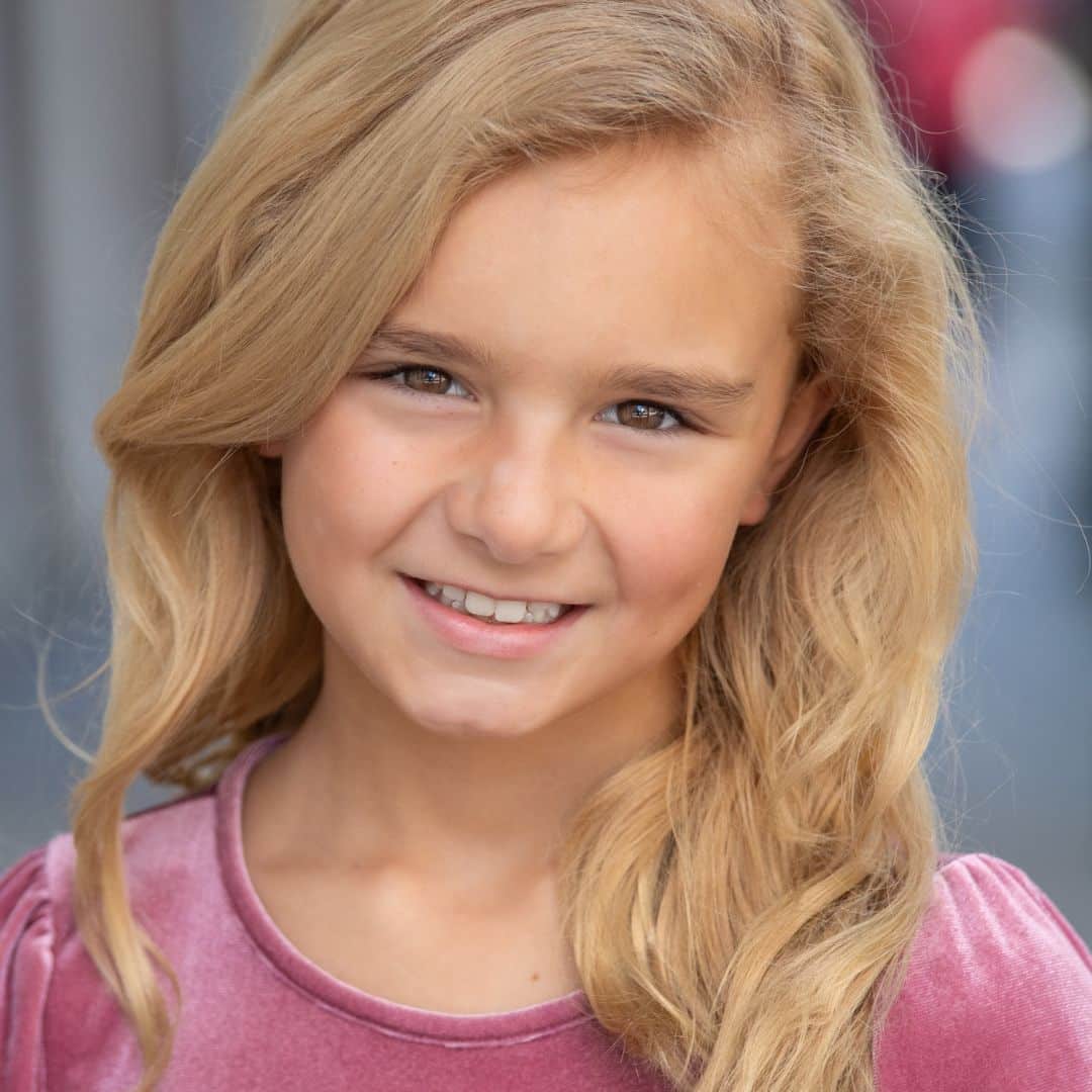 Smiling young girl with blonde hair, natural background.