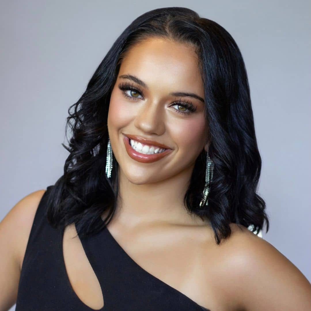 Smiling woman with black hair and earrings.