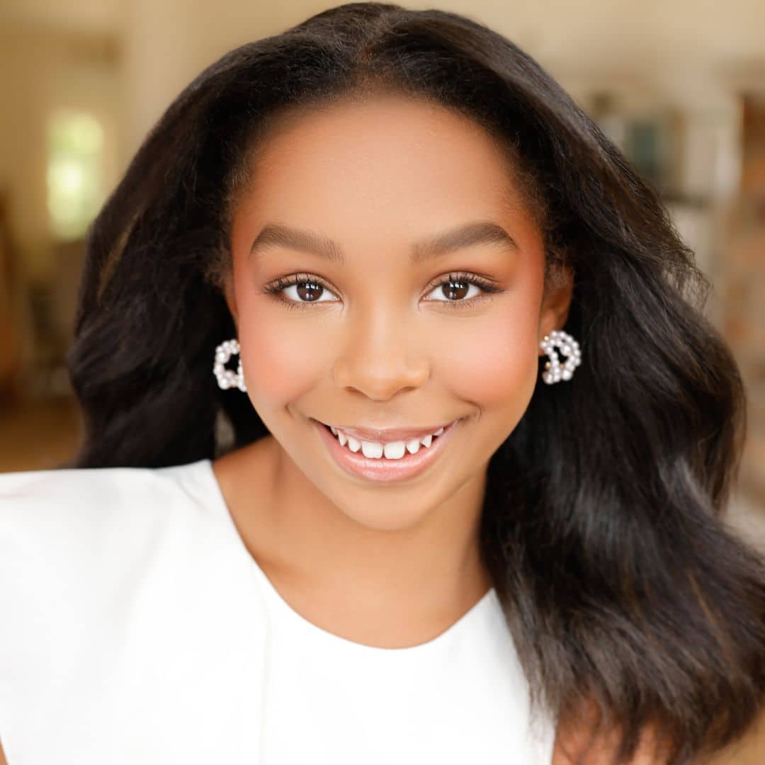 Smiling person with long hair and earrings.