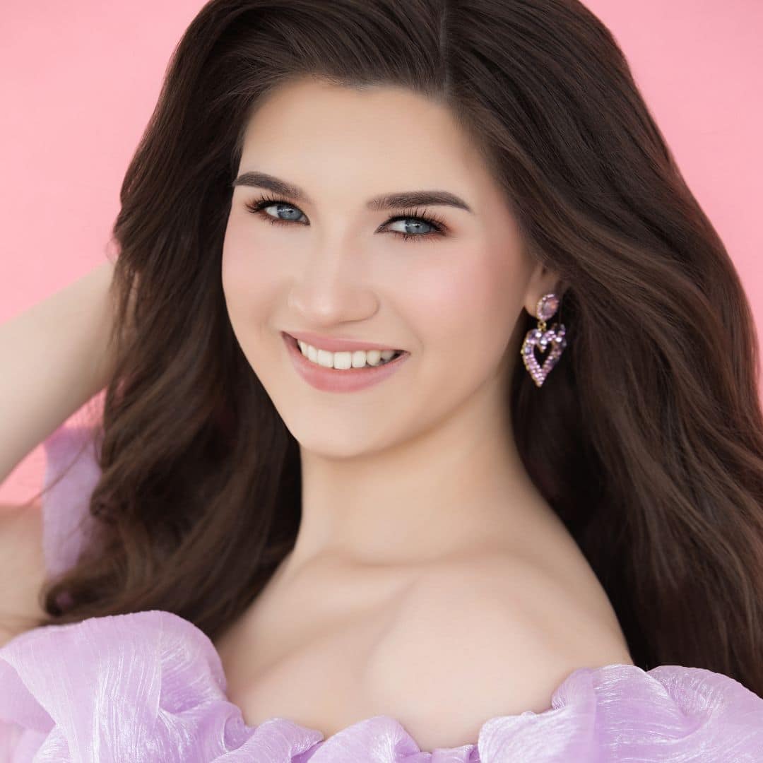 Smiling woman with long hair in pink dress.