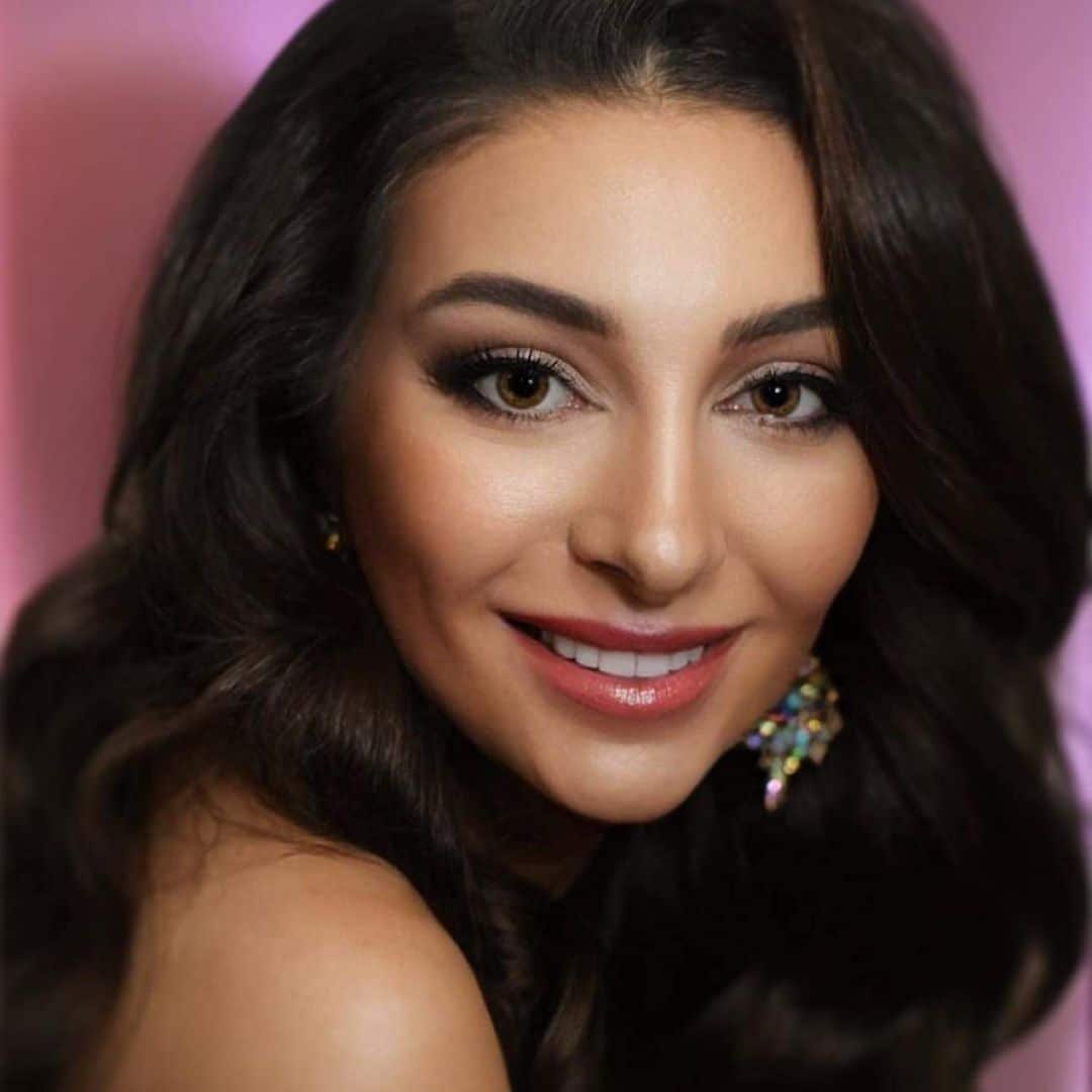 Smiling woman with long dark hair and earrings.