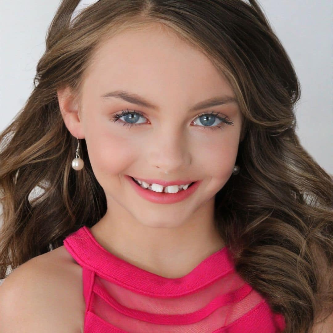 Young girl in pink dress smiling.