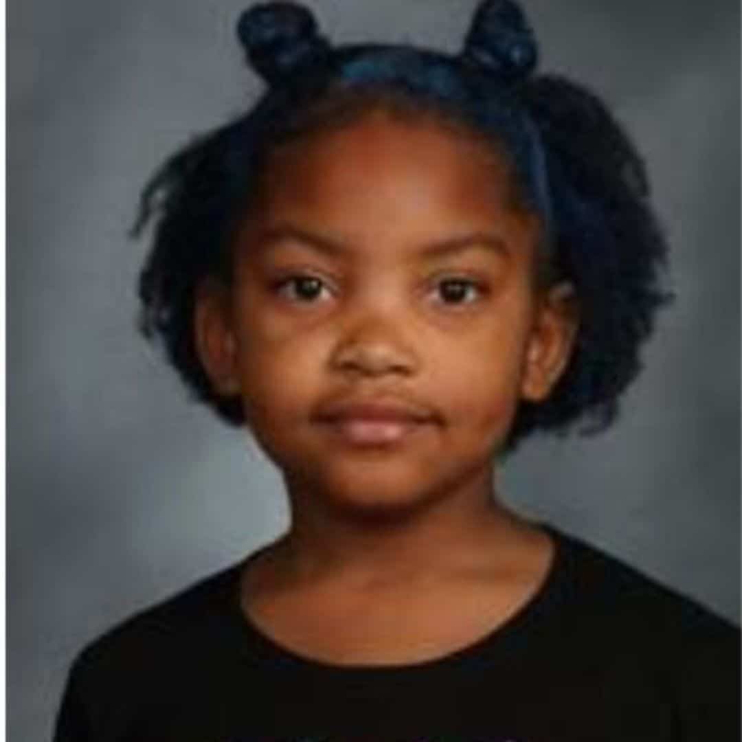 Young girl with curly hair in pigtails.