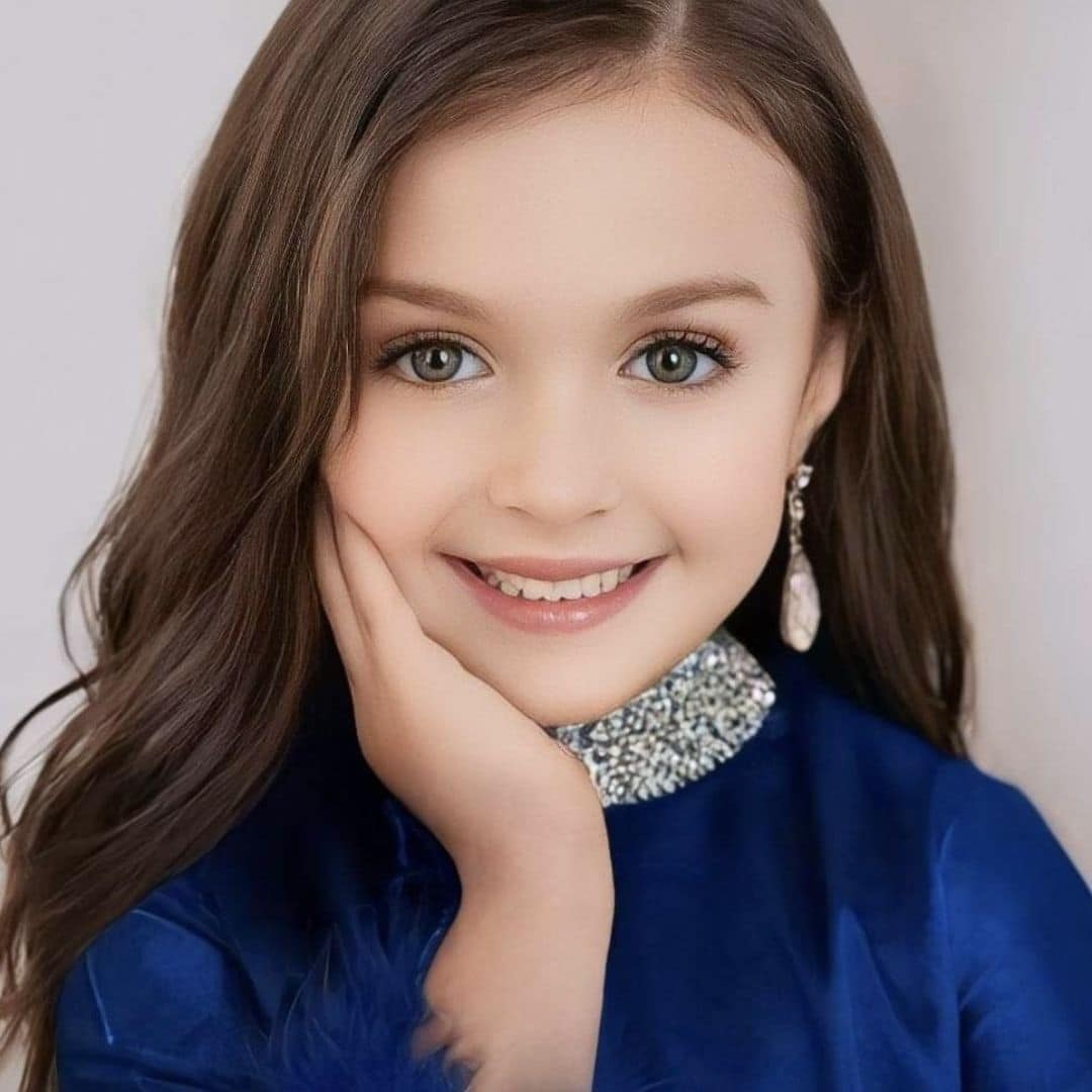 Smiling girl in blue dress with earrings.